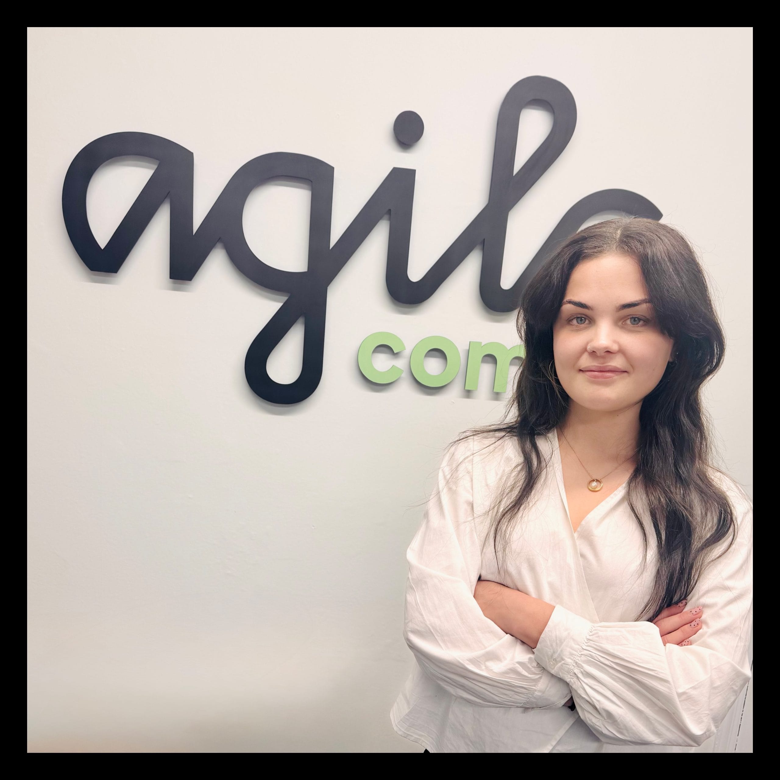 Olivia Evenden in front of the Agile Comms office sign