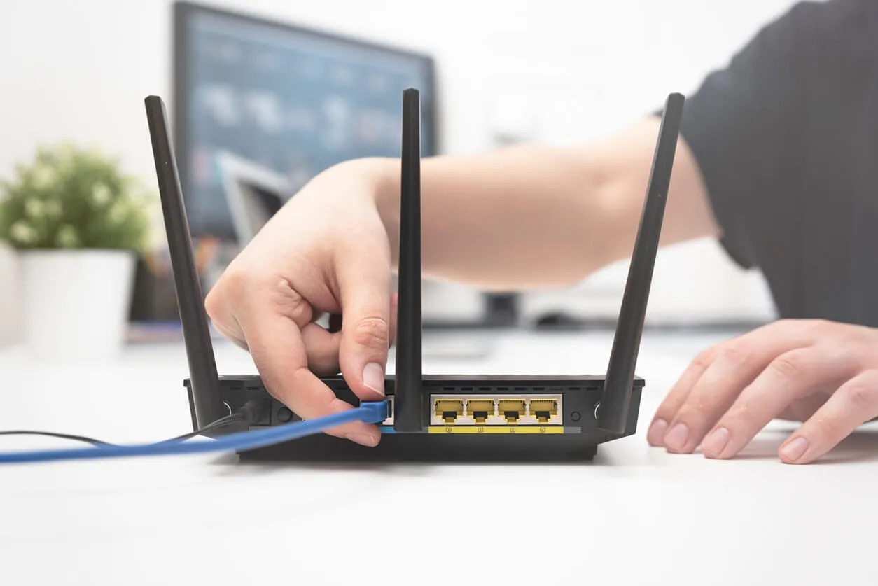 a person plugging in a cable into a broadband router