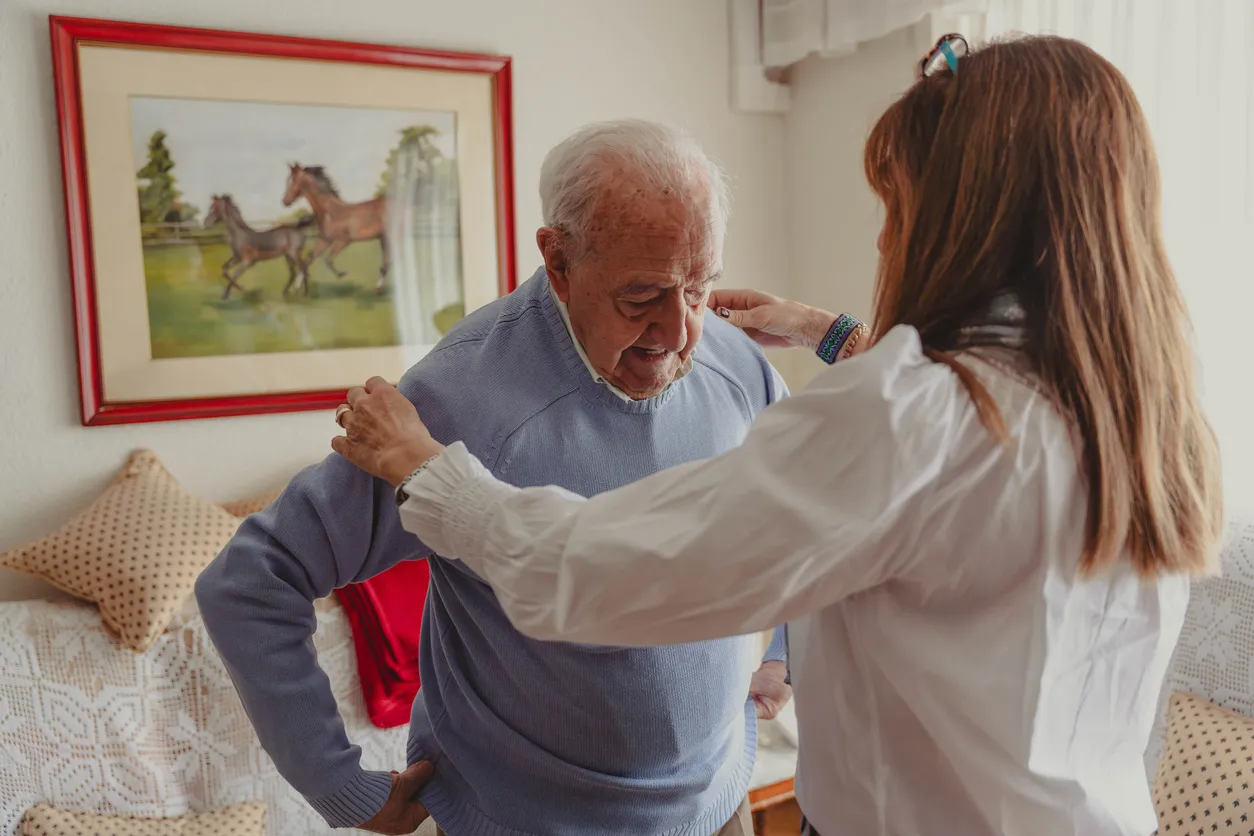 woman helping elderly man get dressed